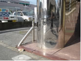 ステンレス鏡面仕上げの柱がへこみ、ステンレス製バリカーも曲がっている。車がぶつかったためと思われる