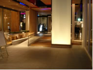 華やかなインテリアやディスプレイに目を奪われやすいところに階段を設けるのは危険。転倒事故の発生により階段が斜路に改修され、斜路が二つ並んでしまった（左の斜路はもとからあったもの）